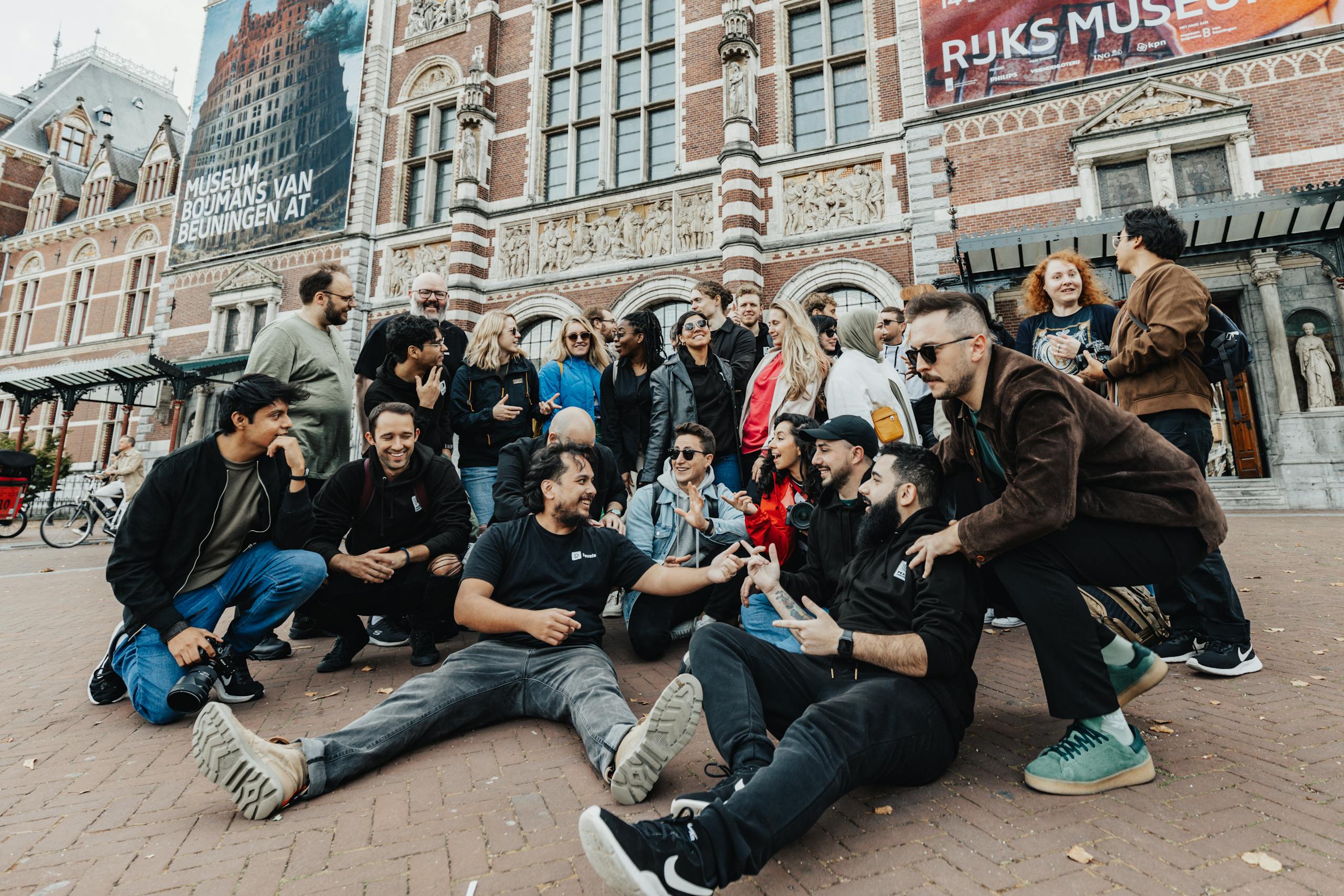 A diverse group of friends gather and enjoy their time in front of Amsterdam's iconic Rijksmuseum.