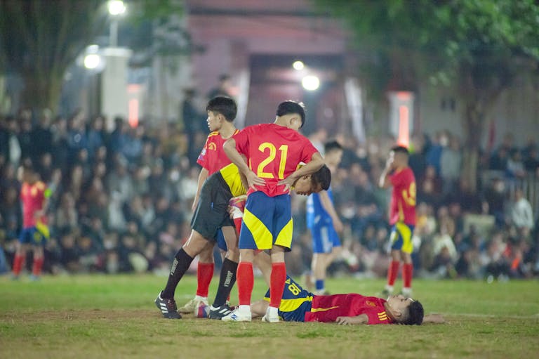 Intense soccer match in Hanoi, capturing players in action at night.