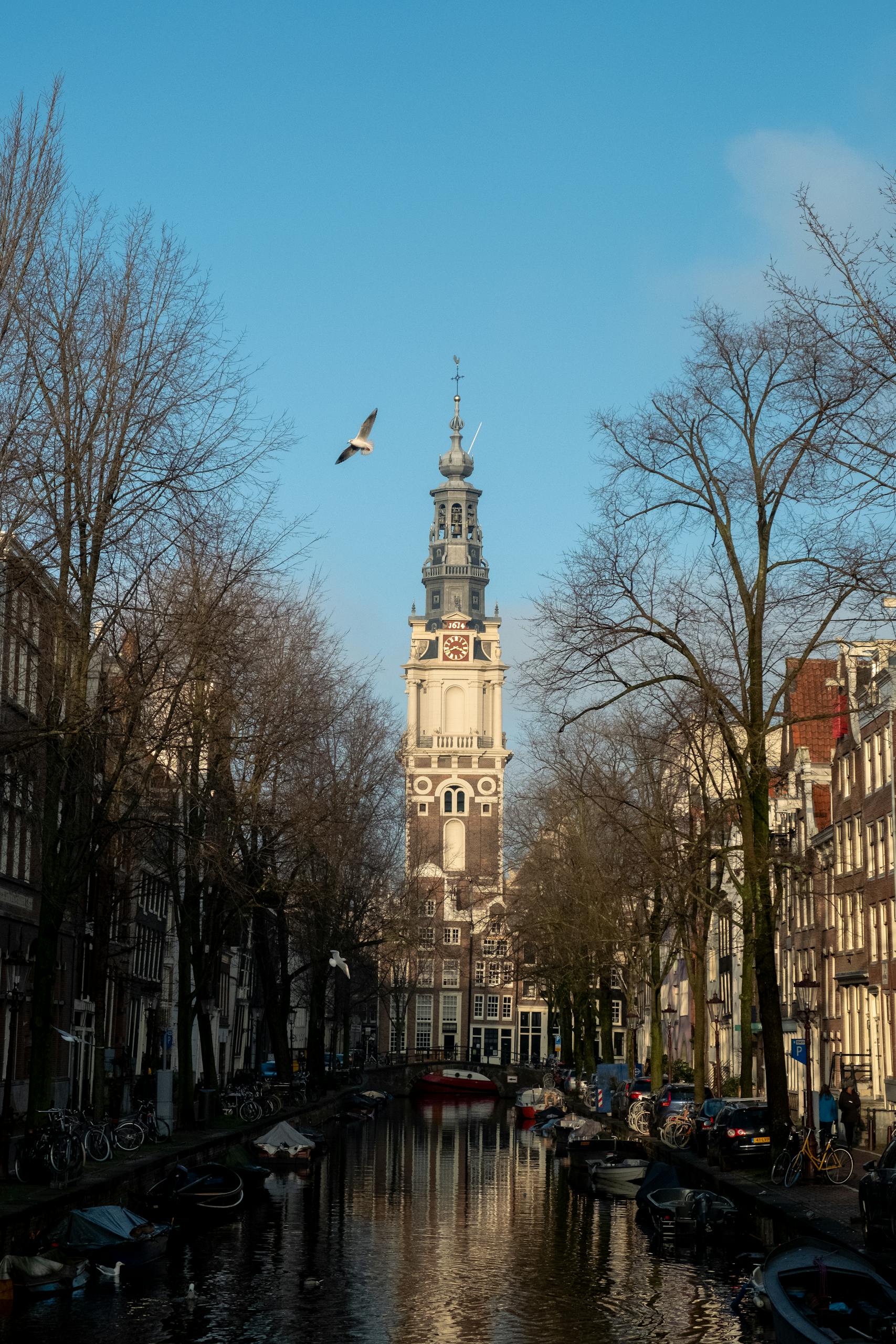 Stunning view of Amsterdam's gothic architecture along a serene canal under a clear blue sky.